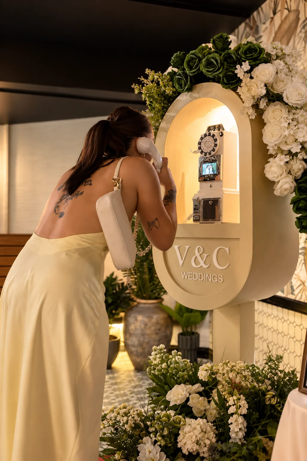Wedding guest in a pale yellow dress recording a telephone message